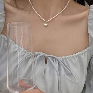 Élégance Féminine : Blouse Bleue, Perles Et Flûte De Champagne Pour Une Occasion Spéciale.