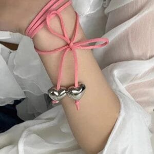 Bracelet Délicat En Cordon Rose Avec Charms En Cœur, Un Accessoire Chic Et Féminin.