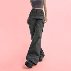 Pantalon cargo olive et top court gris, tendance mode décontractée sur fond rose pastel.