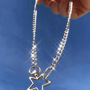 Chaîne En Argent Avec Pendentif Étoile, Capturant Élégance Et Liberté Sous Un Ciel Bleu.