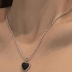 Collier élégant avec pendentif cœur noir, perles argentées, pour une touche chic et moderne.