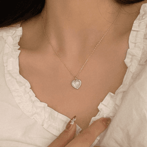 Blouse blanche élégante avec pendentif en cœur, une touche de romantisme moderne.