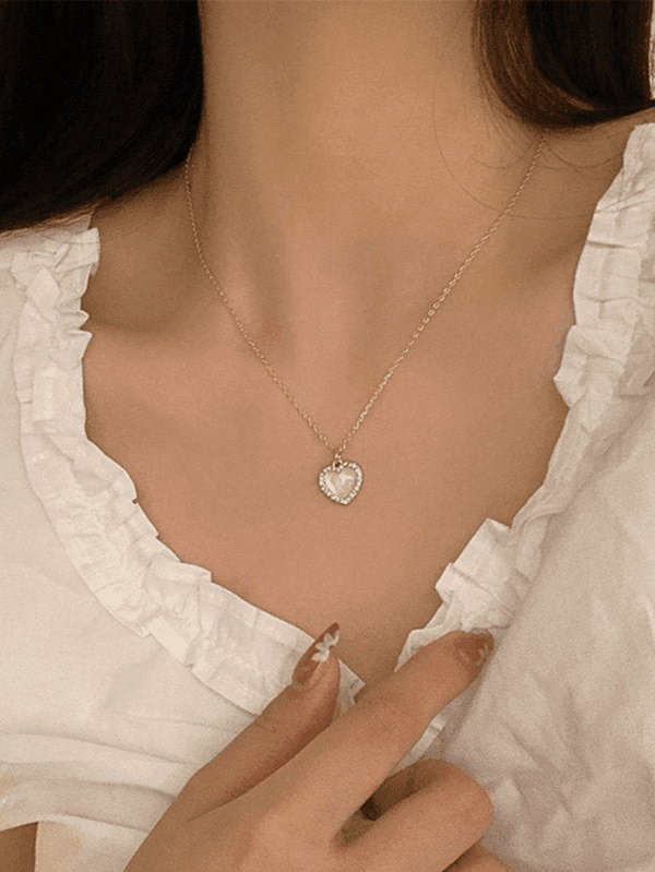 Blouse Blanche Élégante Avec Pendentif En Cœur, Une Touche De Romantisme Moderne.