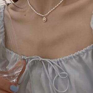 Élégance Douce Avec Collier De Perles Et Blouse Pastel Au Style Raffiné.