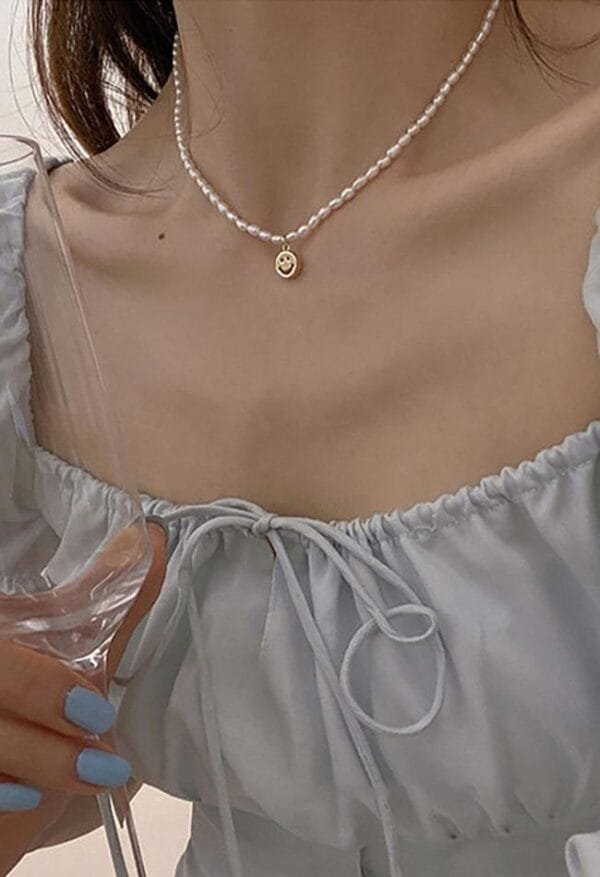 Élégance Douce Avec Collier De Perles Et Blouse Pastel Au Style Raffiné.