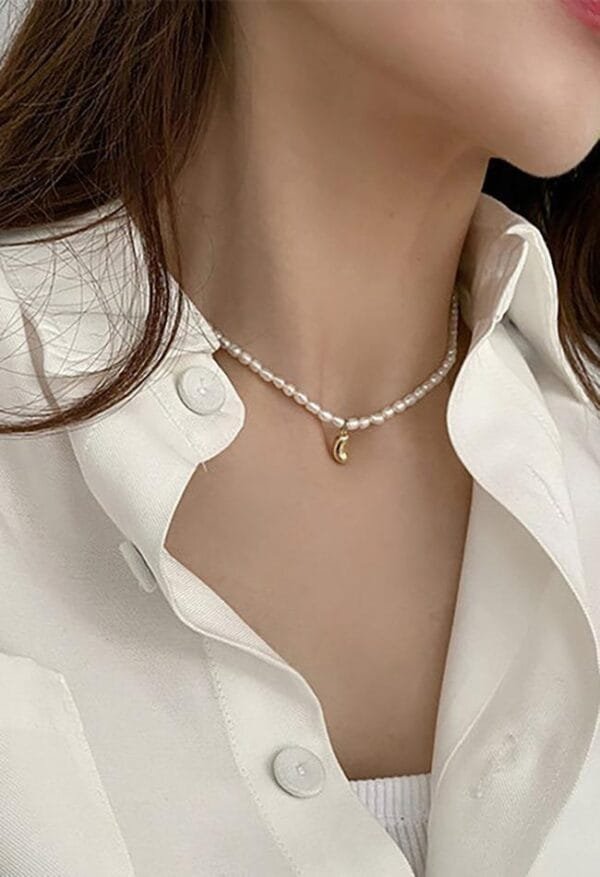 Style Minimaliste : Chic Intemporel Avec Collier En Perles Sur Chemise Blanche Élégante.