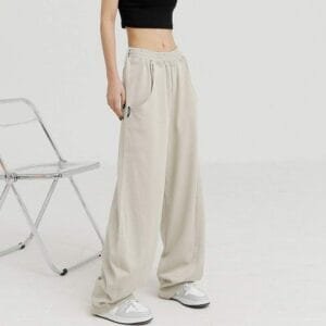 Femme moderne en pantalon large beige et sneakers blanches, alliant confort et style décontracté.