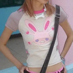 Jeune Personne En Haut Lapin Coloré Et Shorts Roses Contre Un Mur Rose Vibrant.