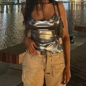 Femme Élégante En Top Argenté Et Pantalon Cargo Au Bord De Leau, Ambiance Urbaine Nocturne.