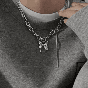 Collier Argenté Avec Pendentif Artistique, Porté Sur Un Pull Gris Confortable Et Décontracté.