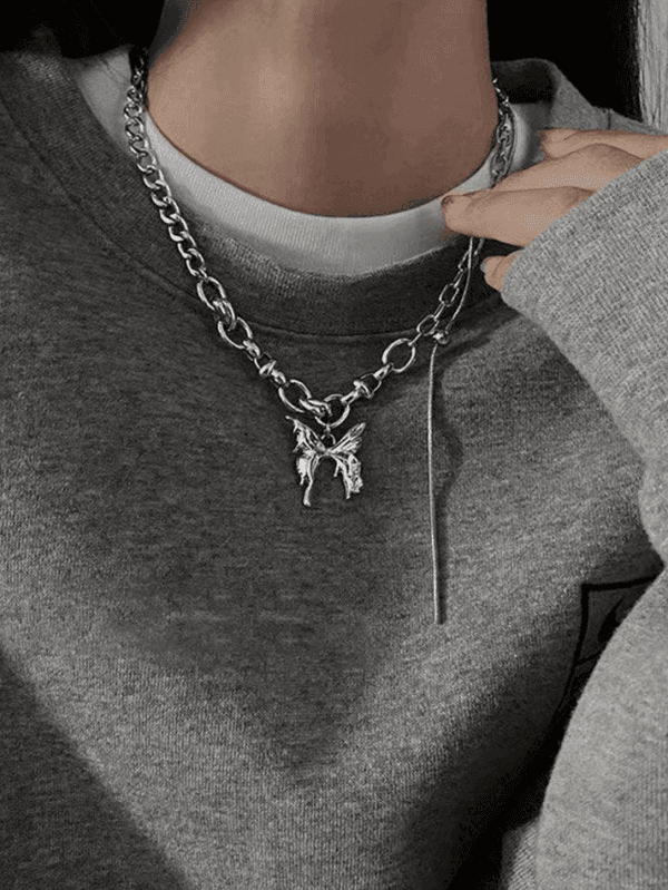 Collier Argenté Avec Pendentif Artistique, Porté Sur Un Pull Gris Confortable Et Décontracté.