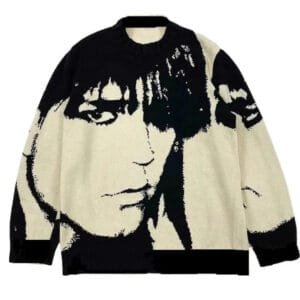 Pull noir et crème avec visages stylisés, alliant confort et style artistique.