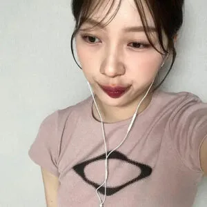 Jeune Femme En T-Shirt Rose Prenant Un Selfie, Écouteurs Aux Oreilles, Style Décontracté.
