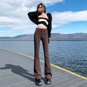 Femme élégante sur un pont au bord de leau, tenue tendance et paysage serein.