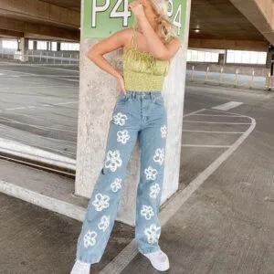 Femme confiante en look tendance, top vert et jeans floraux, dans un parking intérieur.
